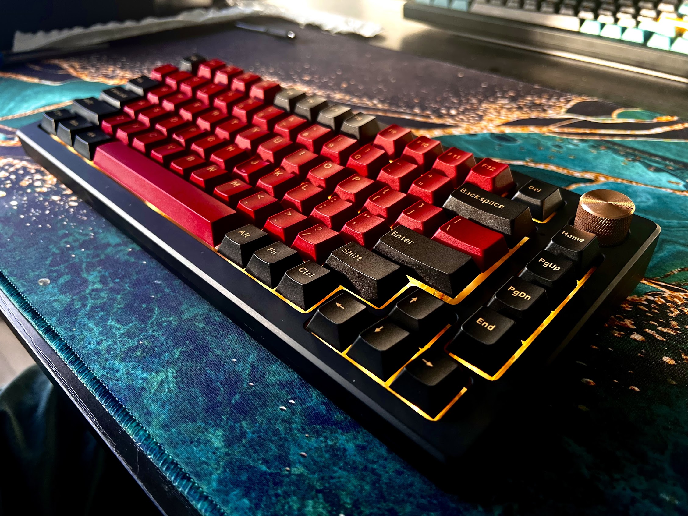 A red and black keyboard, with gold lighting under the keys.